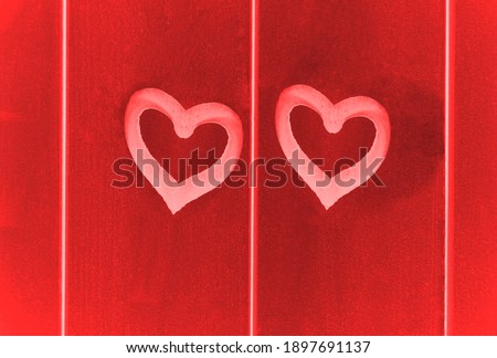 2 two white painted hearts on wooden wall.  red  boards background. happy Valentines day.