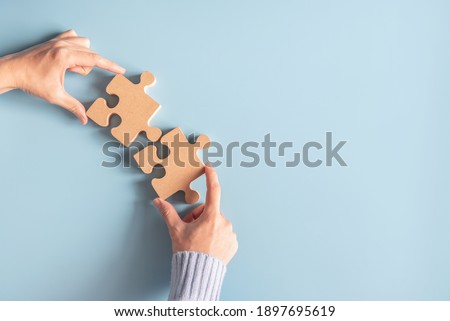Two hands holding jigsaw, Concept for teamwork Building a success.