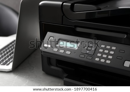 New modern printer and laptop on grey table, closeup