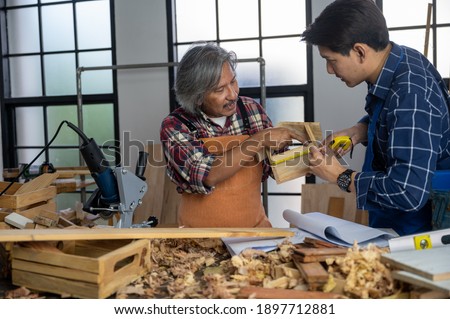 Two adult young Asian Carpenters working and designing the wooden product to build home in workshop. Craftsman makes own successful small business.