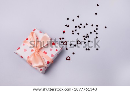 Gift Box with Bow on Light Blue Background Red Confetti Top View Horizontal Holiday Concept or Background Valentine Day