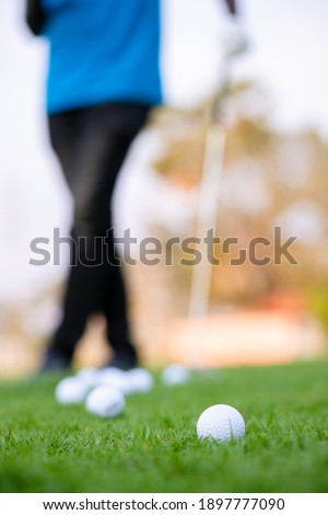 
Green grass with golf ball close-up in soft focus at sunlight and have blur background with man relax after end game.