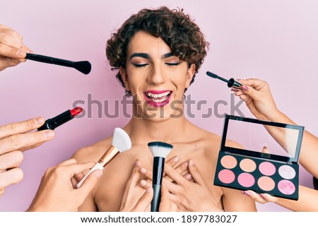 Young man wearing woman make up with stylist all around him smiling with hands on chest, eyes closed with grateful gesture on face. health concept. 