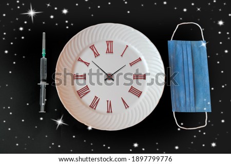 Porcelain plate, mask and syringe. Black background. Covid-19 design. The Covid-19 outbreak is declining.