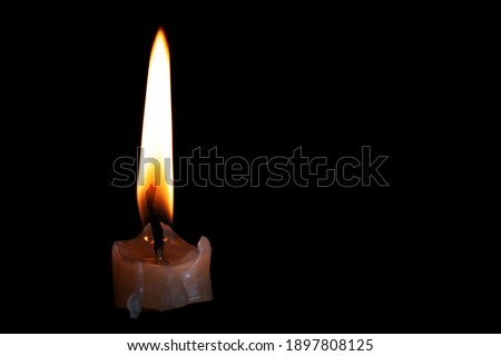 On a black background, the bright light of the candle burns down brightly