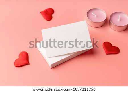 Valentines Day. Stack of visit cards on pink background with hearts and candles for mock up design