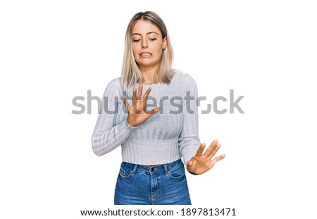 Beautiful blonde woman wearing casual clothes disgusted expression, displeased and fearful doing disgust face because aversion reaction.  Royalty-Free Stock Photo #1897813471
