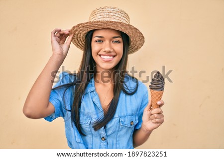 Young latin tourist girl on vacation smiling happy eating ice cream walking at the city.