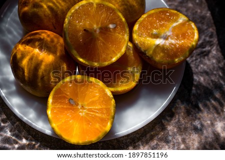 photography of slices and whole oranges with water reflection