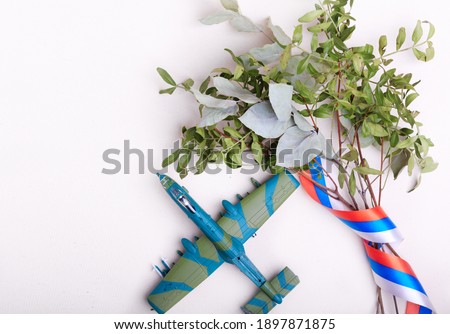 Airplane and a bouquet with a Russian ribbon on a light background. Copy space