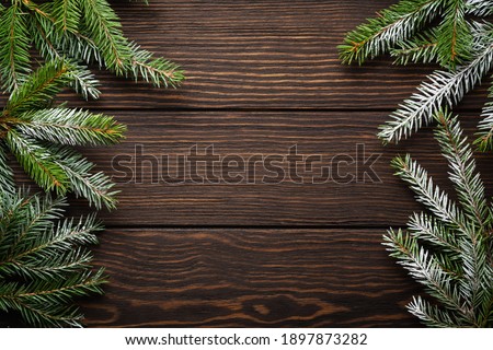Christmas or New Year background with fir branches on the right and left side on dark wooden background. Place for your text.