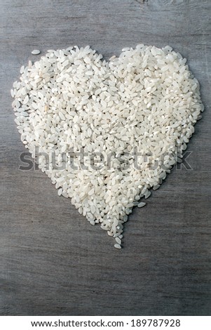 heart of rice grains on wooden background, close-up