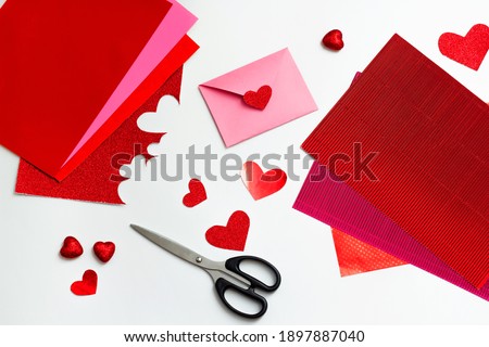 Valentines day craft top view. Handmade valentine card, DIY present. Wedding decoration. Paper, envelope and scissors.