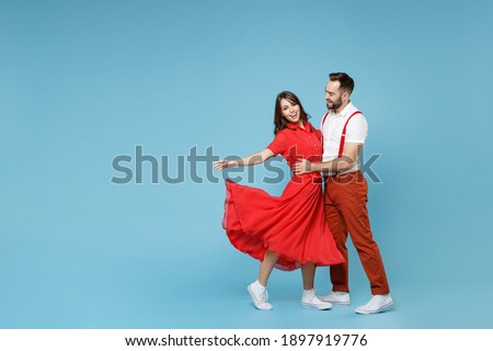 Full length of funny young couple two friends man woman in white red clothes hugging dancing having fun isolated on pastel blue color background studio portrait. St. Valentine's Day holiday concept