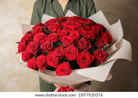 Woman holding luxury bouquet of fresh red roses on light background, closeup Royalty-Free Stock Photo #1897920376