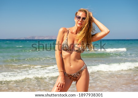 Gorgeous fashion model posing on a sand beach. Summer holiday concept.