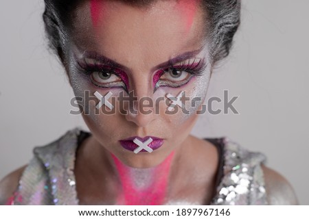 Emotional Young Woman with creative pink purple make-up and with bright fans in her hands posing on a white background in the studio