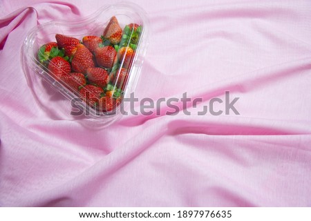 strawberries in a heart-shaped box on a pink background with space for text, February 14 Valentine's day