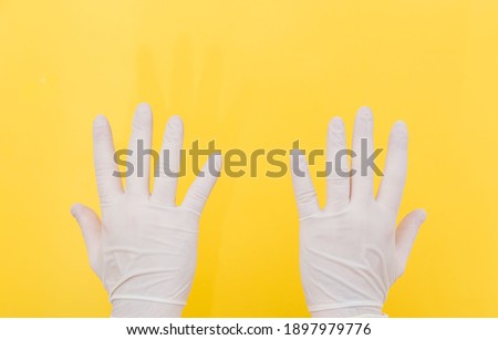 The close plan. Two hands in white medical gloves on a yellow background. The medicine. Place for an inscription. Medical gloves. Advertising. Covid 19.