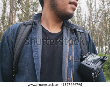 Young man taking photos with his camera while walking through the forest.