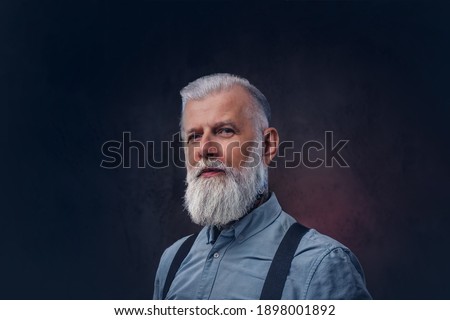 Portrait of elegant and stylish grandfather with modern hairstyle in shirt which poses in dark background. Royalty-Free Stock Photo #1898001892