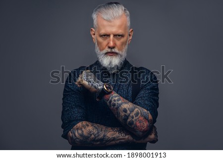Mature and brutal man dressed in fashionable clothing poses in studio background looking at camera. Royalty-Free Stock Photo #1898001913