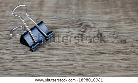 Black Binder Clip on Wooden Surface Background Space for Text