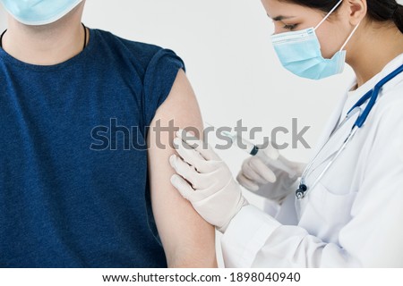 beautiful woman doctor in medical mask giving an injection to a patient vaccination