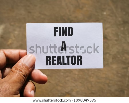 Selective focus image with noise effect hand holding white card with text FIND A REALTOR.Business and property concept.