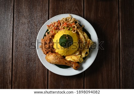 Traditional Indonesian Food known as tumpeng mini nasi kuning. It is a kind of flavored steamed rice, seasoned with turmeric. Served with fried noodle, fried chicken, beef floss and omelette. Royalty-Free Stock Photo #1898094082