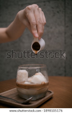 Woman Hands is Pouring Milk into The Cold Lemon Tea or Coffee for Cold Brew Menu. Close-up. Breakfast time. Concept coffee maker pours milk mixed with hot coffee in coffee shop