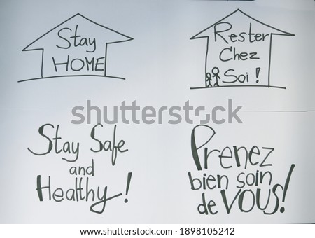Hand writing Stay Home, Stay Safe and Healthy in English and French drawing on white paper. Coronavirus or COVID-19 concept.
French text means Stay home, Stay Safe and Healthy. 