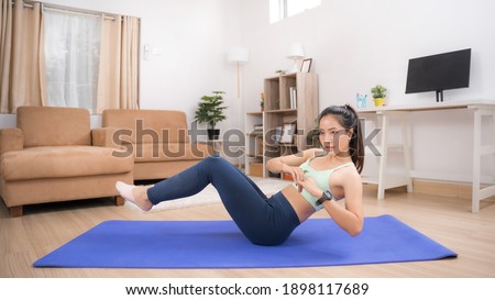 Asian woman exercising at home, she is doing a Russian twist. Royalty-Free Stock Photo #1898117689