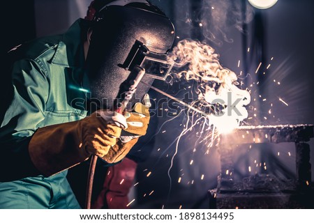 Metal welding steel works using electric arc welding machine to weld steel at factory. Metalwork manufacturing and construction maintenance service by manual skill labor concept. Royalty-Free Stock Photo #1898134495