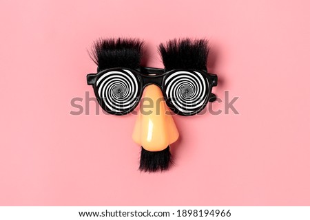 funny face - fake eyeglasses, nose and mustache on pink background Happy fools day  concept  1st April party Holiday card Royalty-Free Stock Photo #1898194966