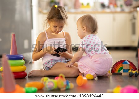 Two children play toys, girls one year old and six years old