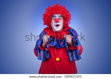 Happy clown in red costume on blue background. Studio professional lighting