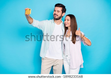Photo of two positive persons make selfie lady show thumb up good mood wear stylish isolated on blue color background