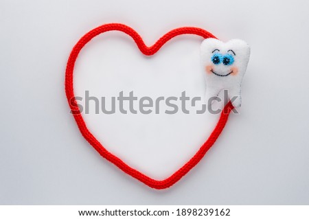 White felt tooth with red heart on white background. Dental health concept. World dentist day concept. Flat lay, top view, copy space.