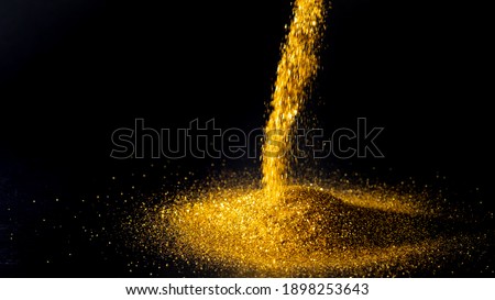 Sprinkle gold dust on a black background with copy space.