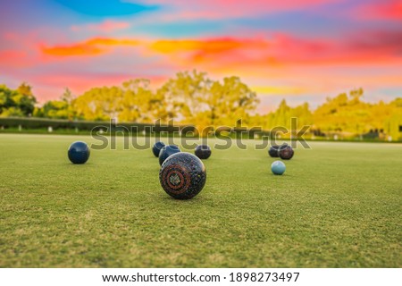 Lawn bowls balls in a field after the game with a colourful sunset Royalty-Free Stock Photo #1898273497
