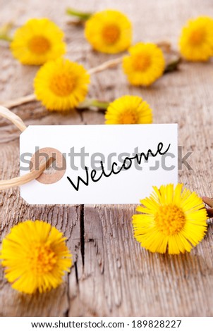 Tag with Welcome and yellow Flowers on Wood
