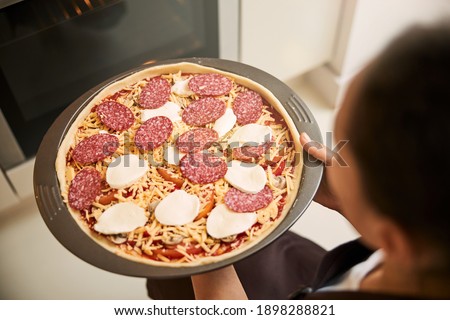 Close up of a baking pan with delicious pizza ready to be placed into the oven