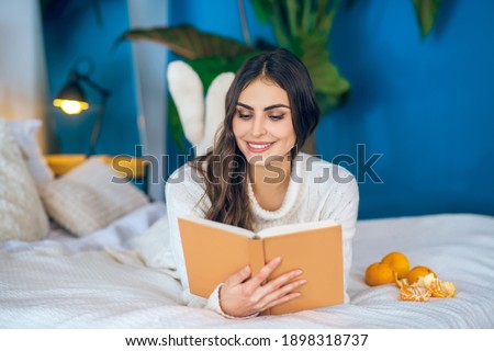 Funny story. Young beautiful woman reading a book and smiling