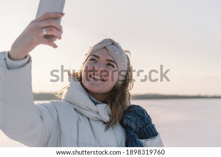 A woman makes a selfie on the phone in the winter. Winter holiday.