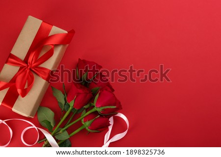 Beautiful gift box and roses on red background, flat lay with space for text. Valentine's day celebration Royalty-Free Stock Photo #1898325736