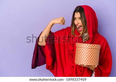 Young indian woman wearing a hijab holding a valentines day gift isolated raising fist after a victory, winner concept.