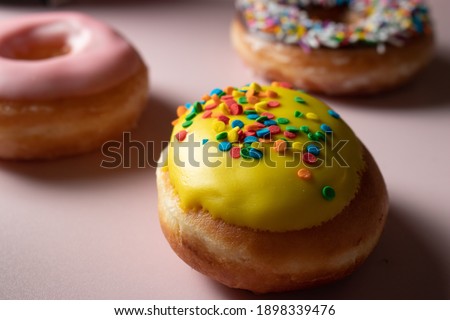 Donut flat lay on pink background. Colourful sweets with chocolate and sprinkles. Minimal flat lay of glazed doughnuts shot in a trendy, minimal style in studio. Junk food in pastel colours. 