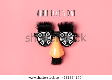 funny face - fake eyeglasses, nose and mustache on pink background Happy fools day  concept  1st April party Holiday card Royalty-Free Stock Photo #1898349724