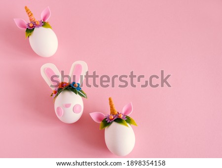Top view flat lay easter eggs unicorns and rabbit on a pastel pink background. Minimal easter card. Copy space. 
